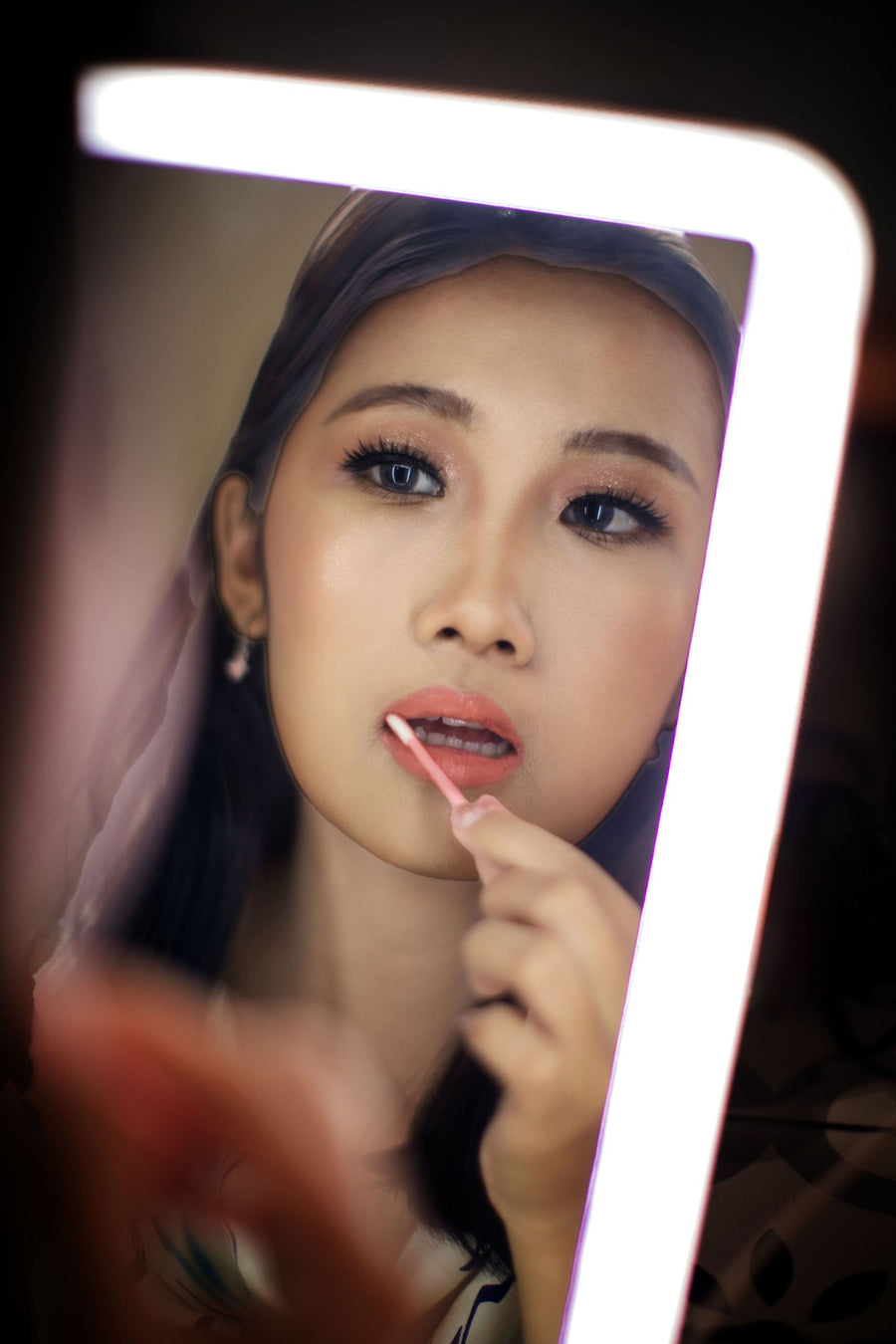Femme se maquillant devant un miroir éclairé par des LED